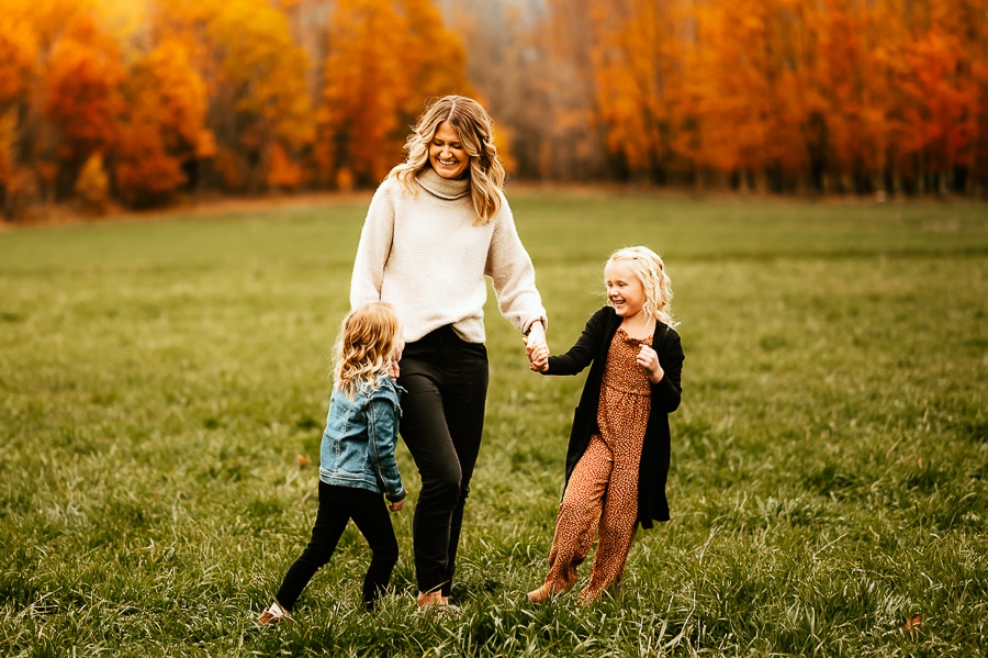 Mother and daughters walking through field in fall