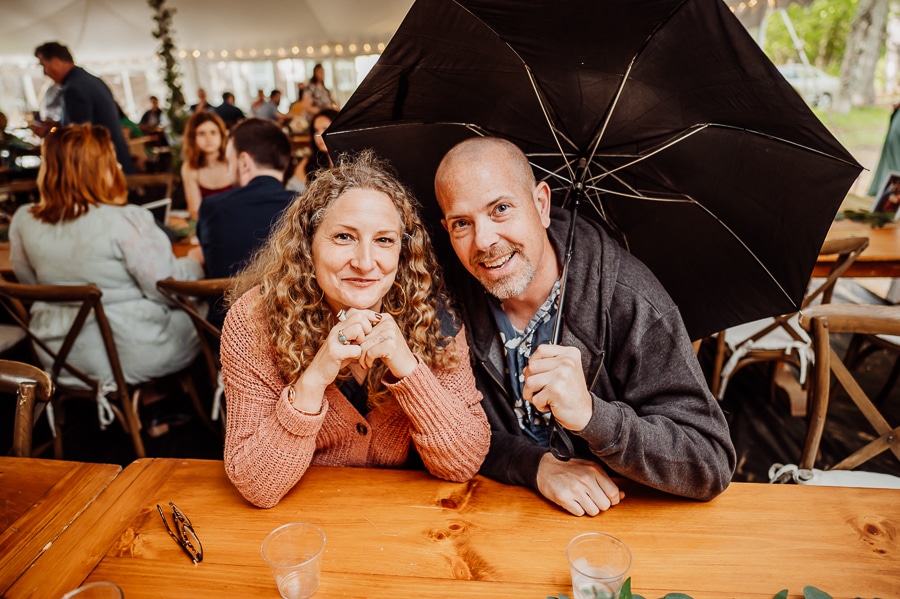 Wedding guests smiling at table with black umbrella