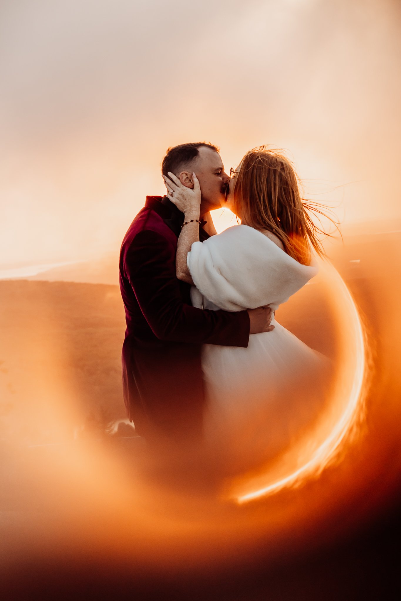 Bride and groom kissing with golden ring of fire around them