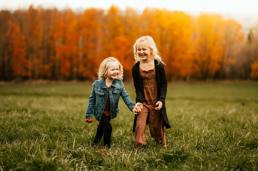 Two little girls walking together in fall field