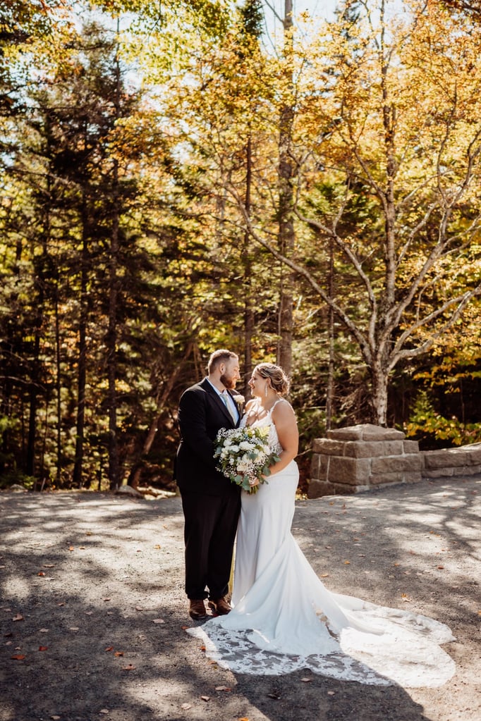 Bride and groom sharing a quiet moment under the autumn trees at Jordan Pond in Acadia National Park.