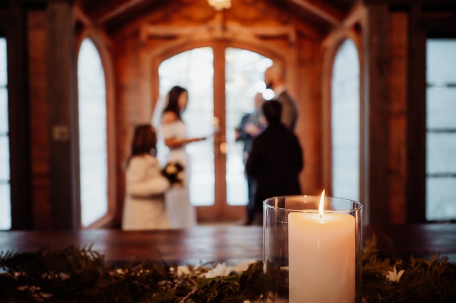 Indoor winter wedding ceremony with candle on table in focus