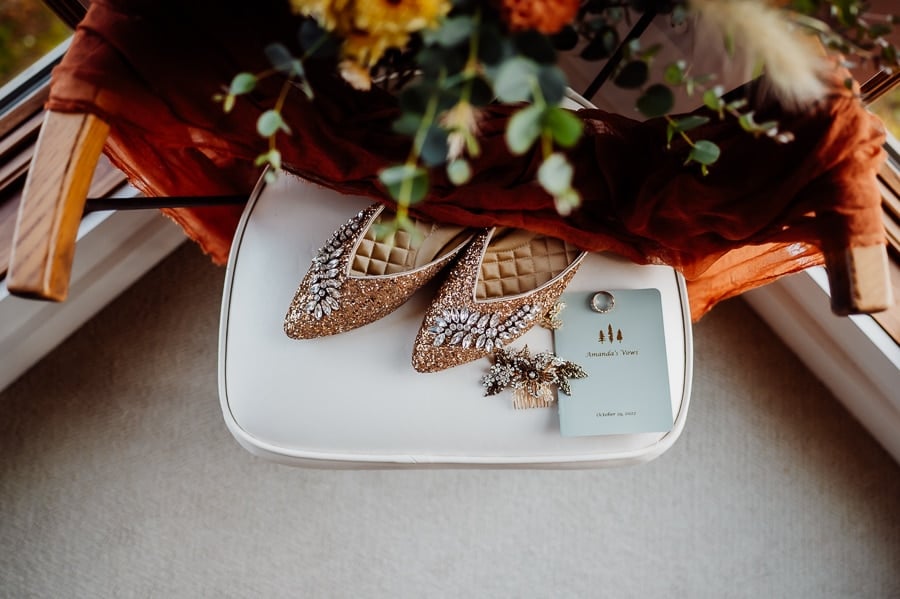 wedding shoes with vow book and rings in chair from above