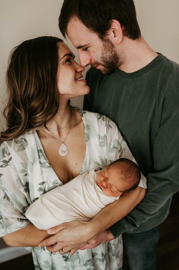 Mother and father looking at each other holding newborn baby