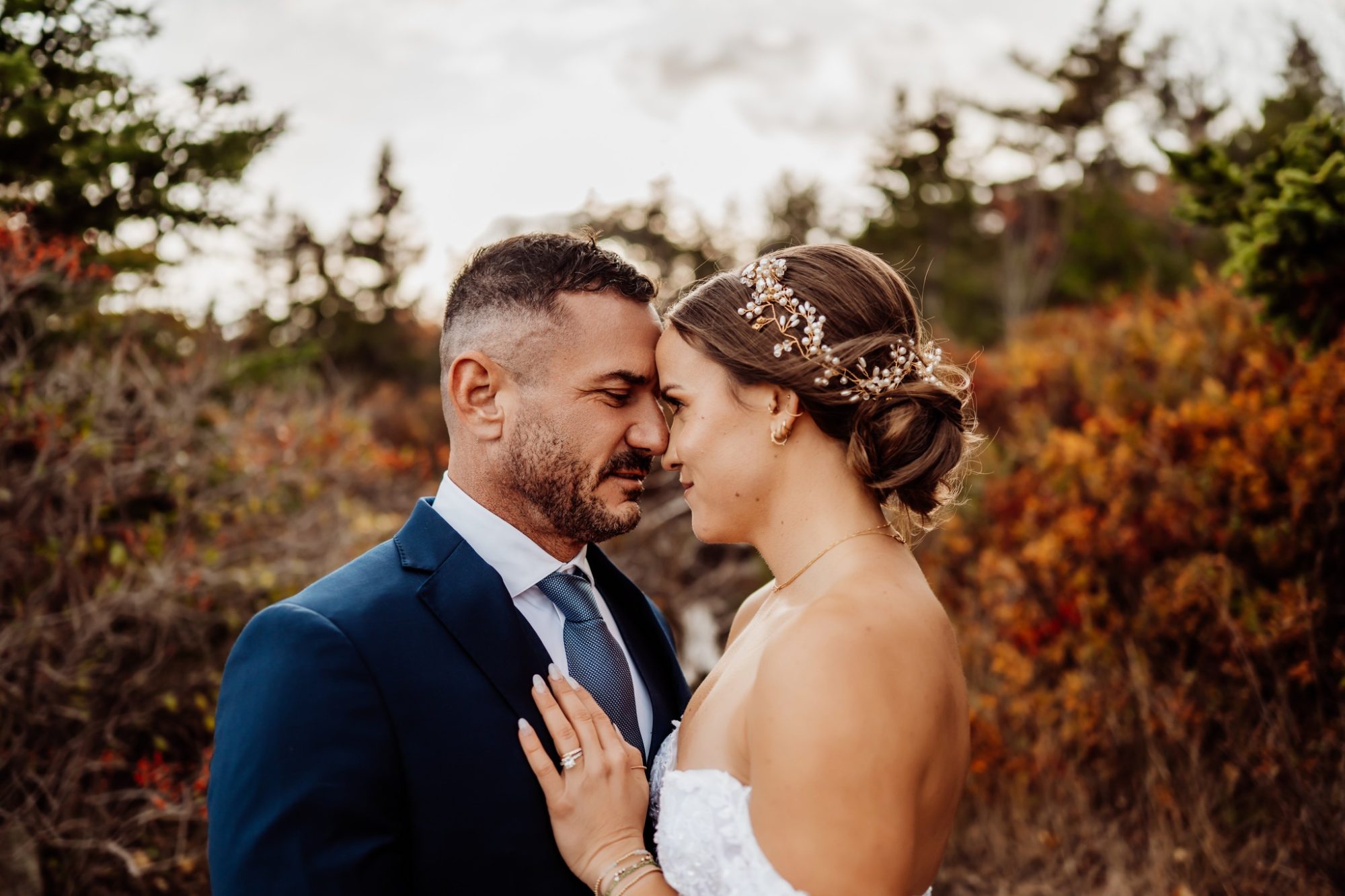 Romantic close-up of bride and groom embracing during their fall elopement in Acadia National Park.