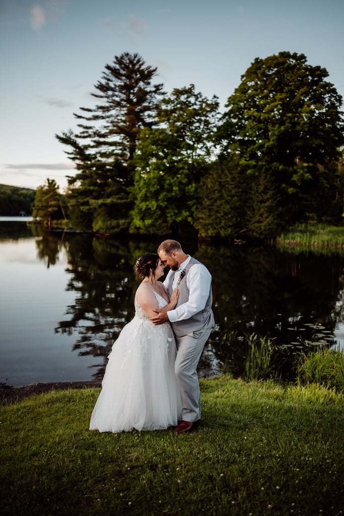 bride and groom facing and embracing each other in front of pond