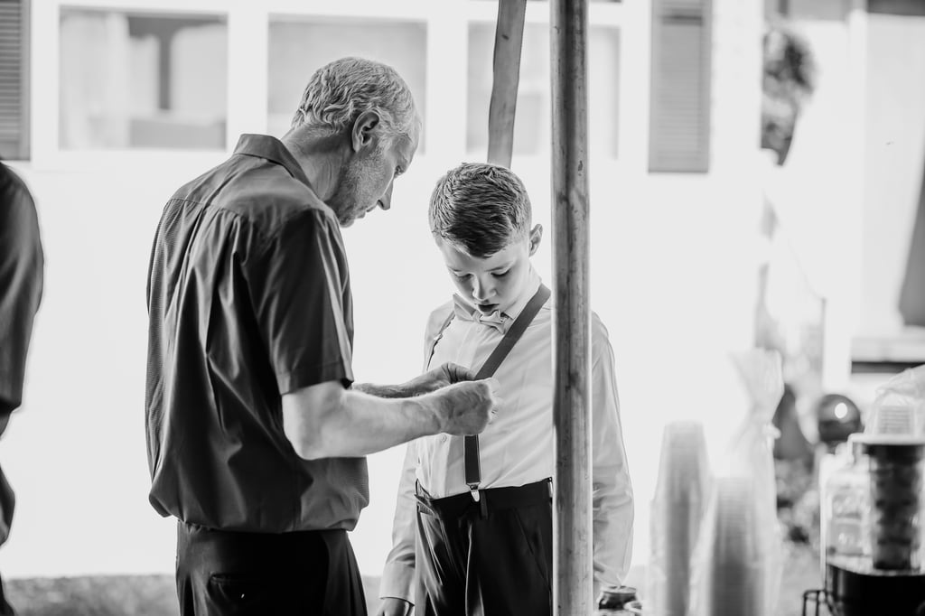 A man helps a boy adjust his suspenders.