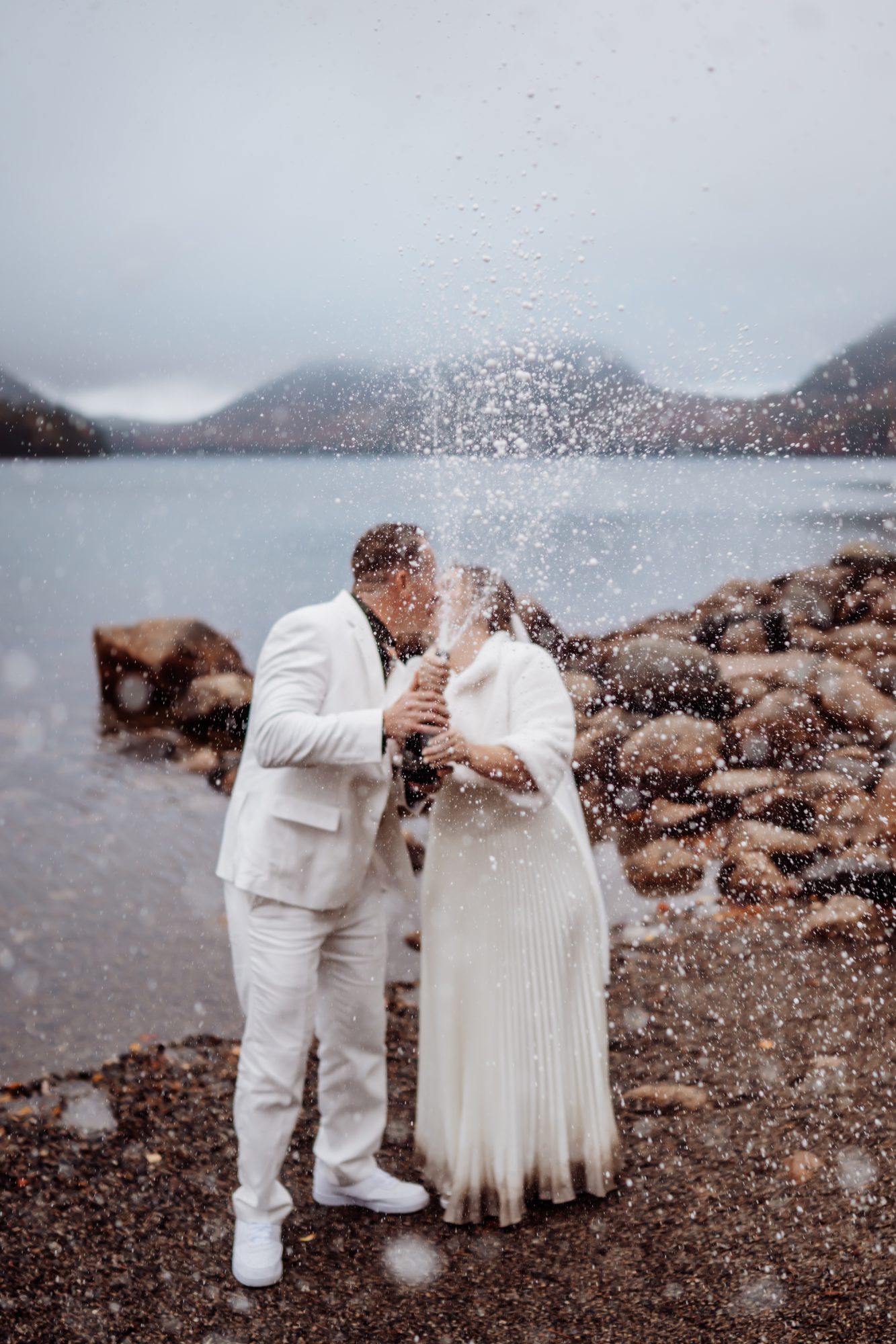Champagne spray celebration during fall elopement at Jordan Pond in Acadia National Park.