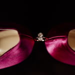 wedding ring placed between heels on pink wedding jimmy choo shoes