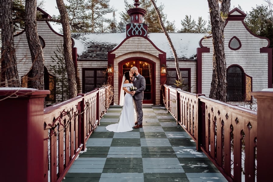 Bride and groom standing in walkway kissing in front of building