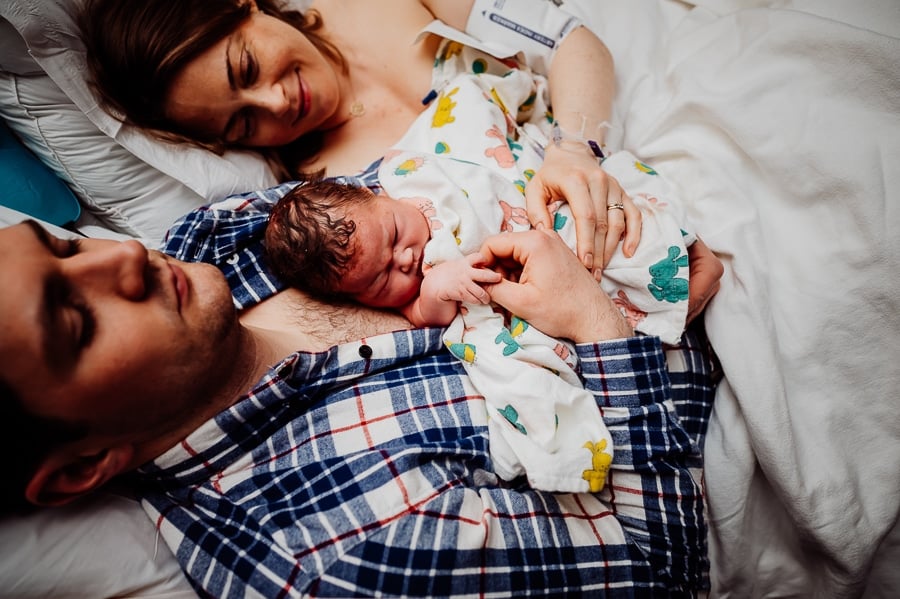 Father doing skin to skin with newborn baby in hospital bed