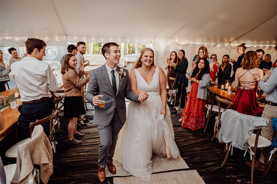 Bride and groom entering wedding reception together among crowd