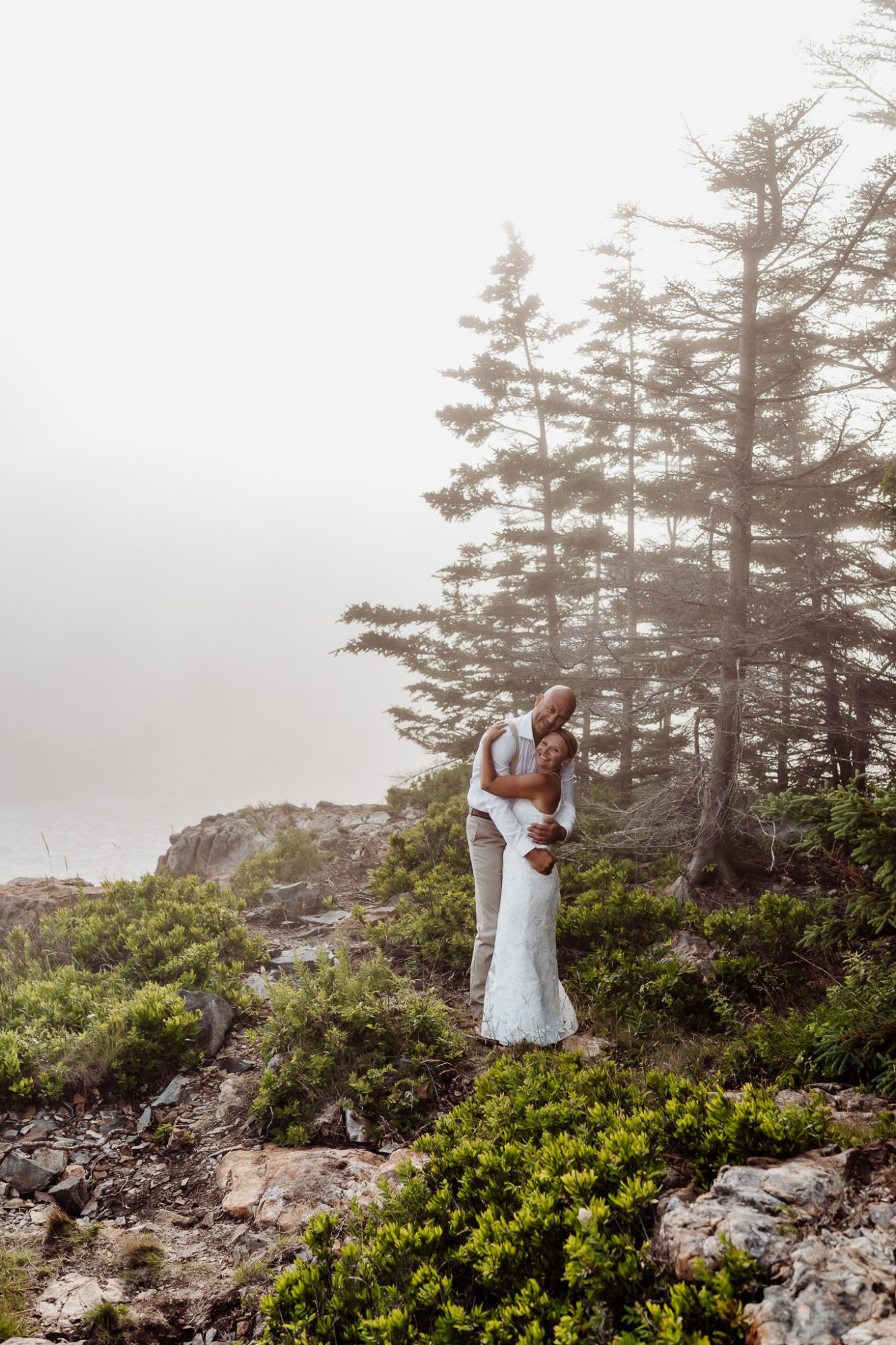 Bride and groom standing in acadia in the fog