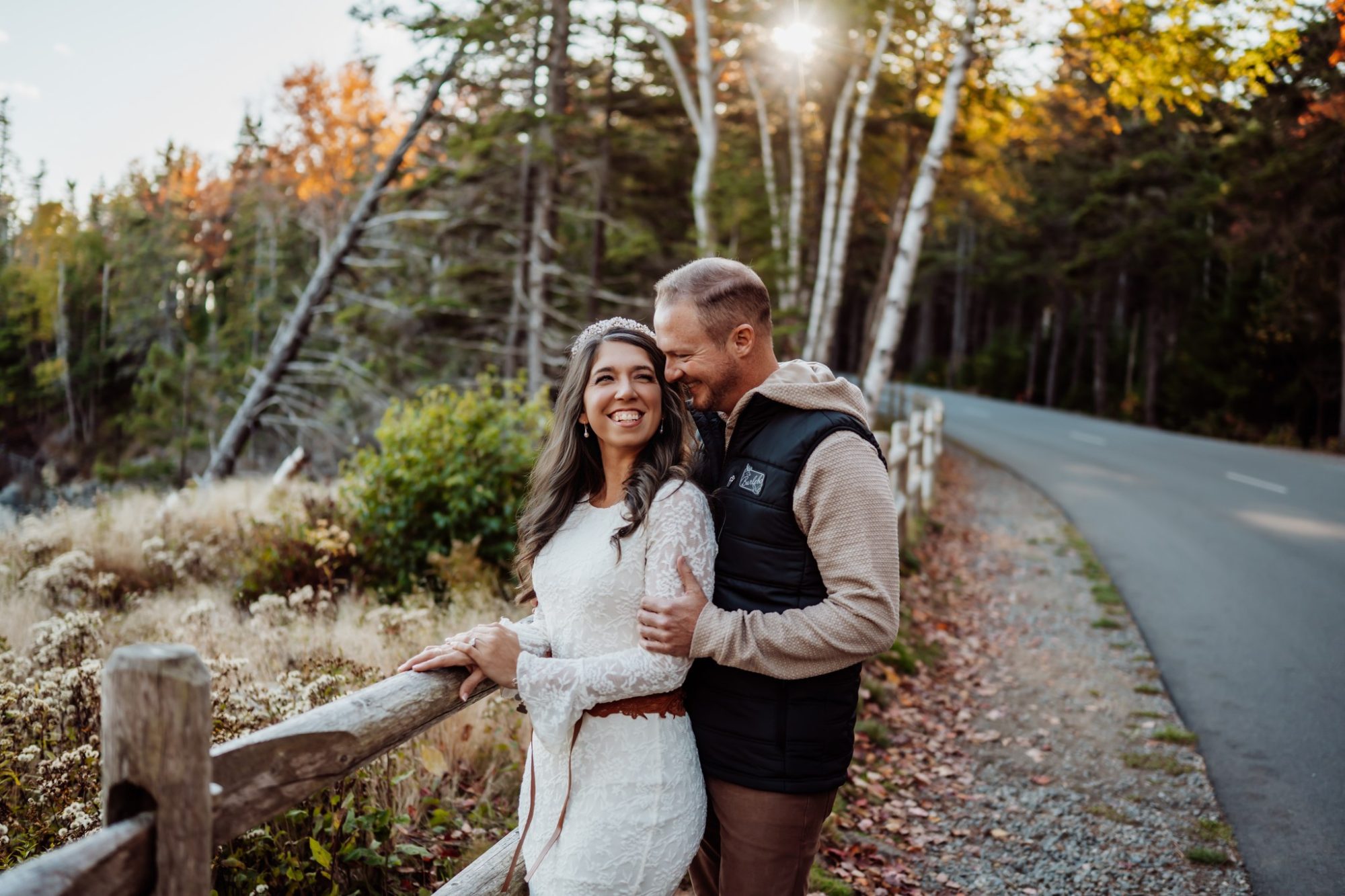 Newlyweds smiling along wooded Park Loop Road during fall elopement in Acadia.