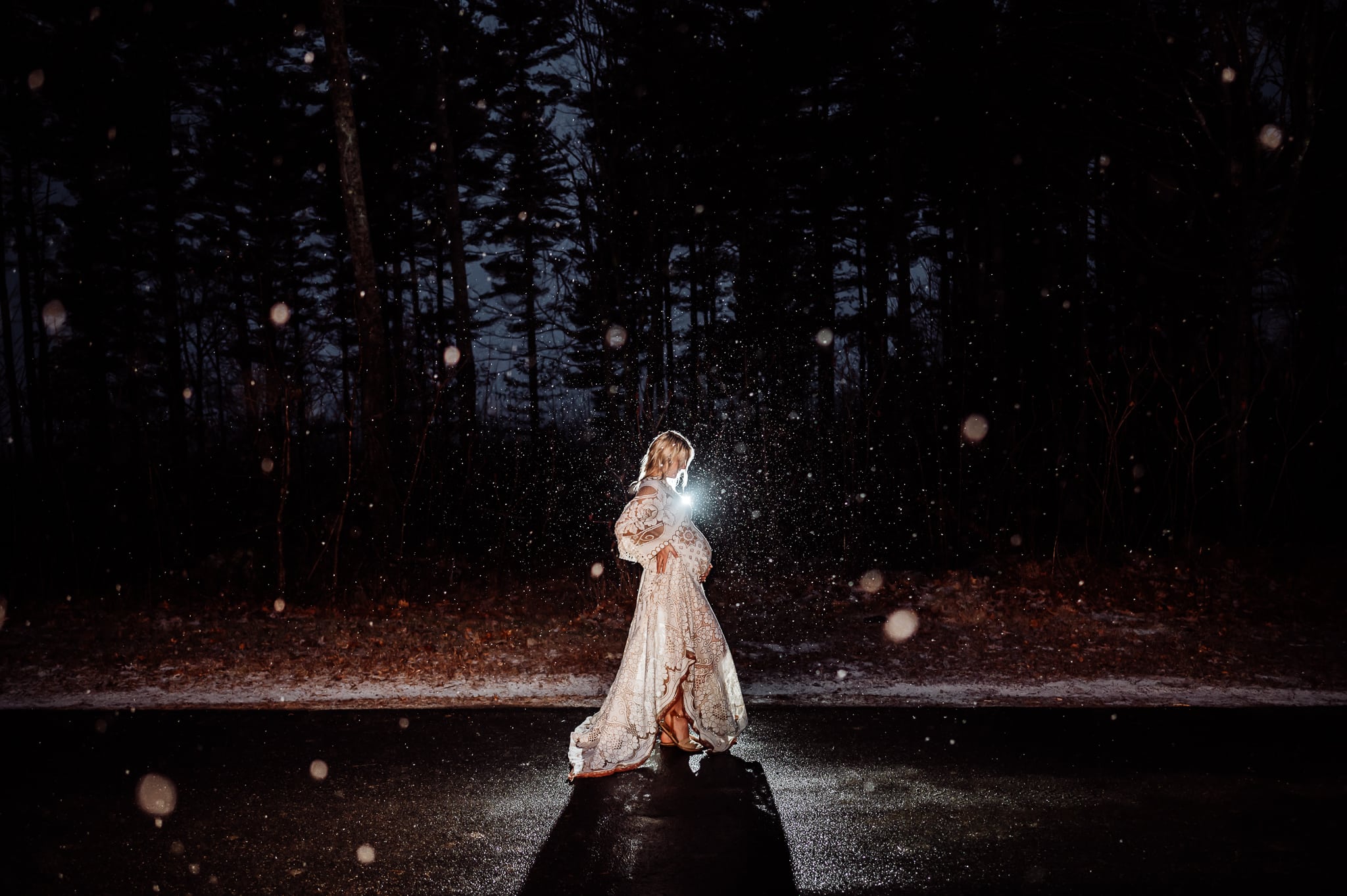 Woman wearing white dress in maternity at night in the snow