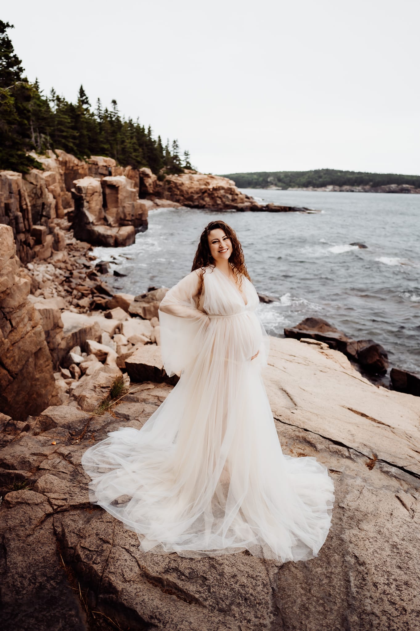 Woman standing on rocky cliffs with a big white dress