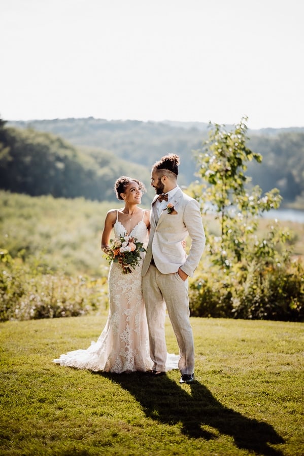 Bride and groom posing in front of orchard at Clarks cove inn
