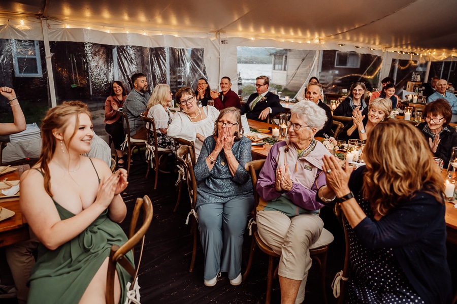 Crowd at wedding cheering at tables during speech