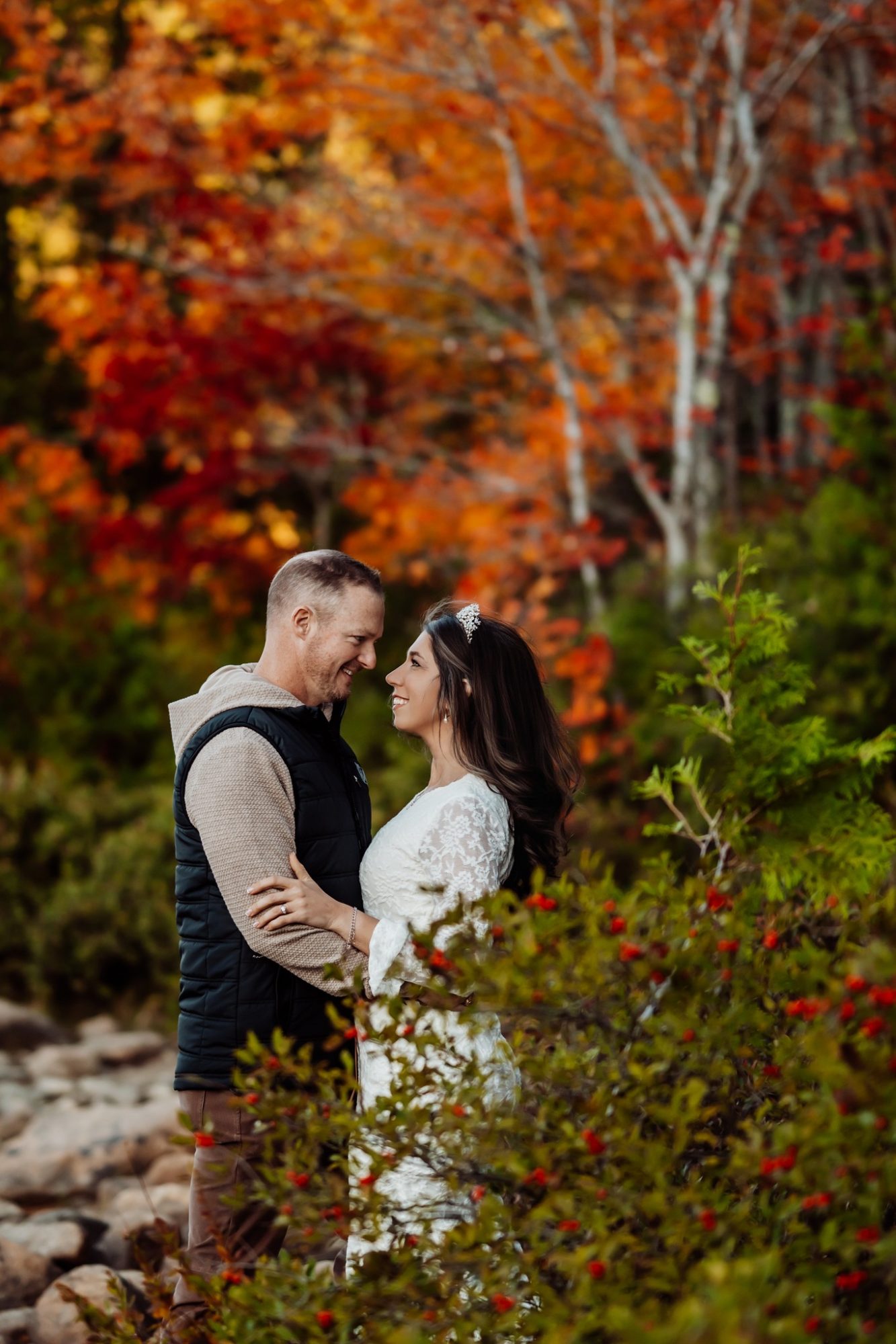 Couple framed by red autumn leaves during intimate Acadia elopement.