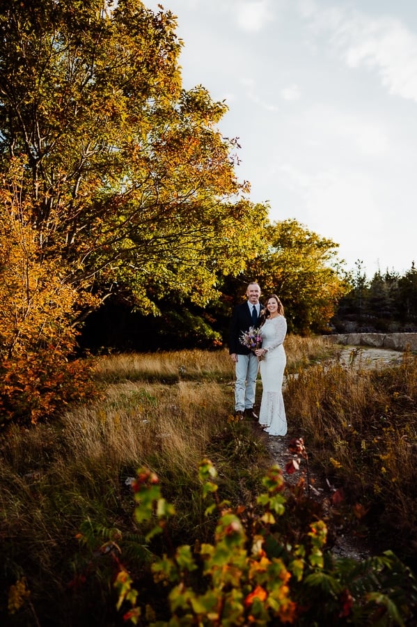 Bride and groom in acadia national park in front of trees