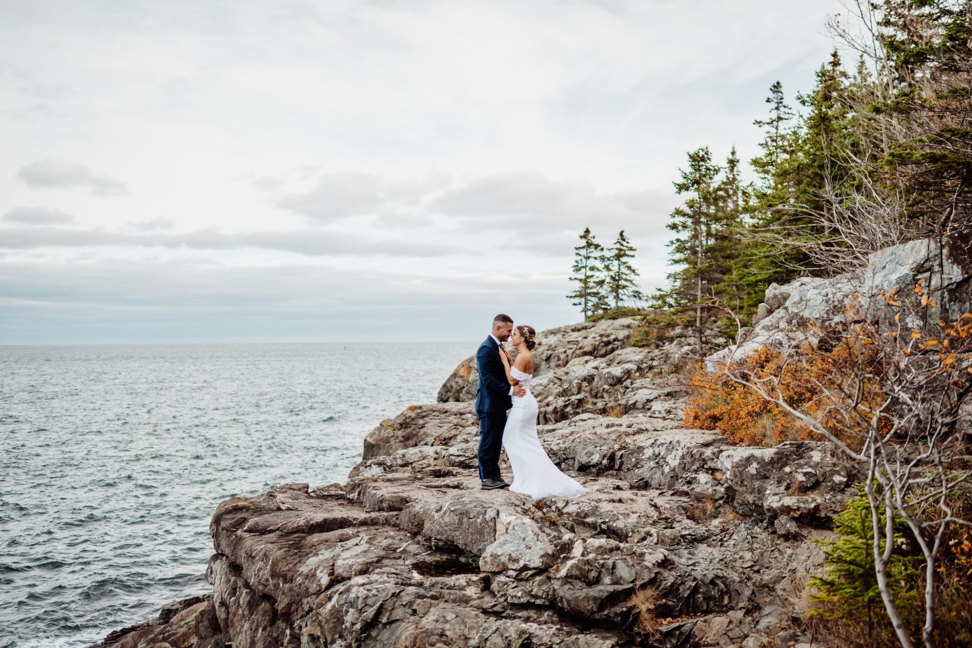 Bride and groom standing on rugged coastal cliffs during their Schooner Head Overlook elopement in Acadia National Park.