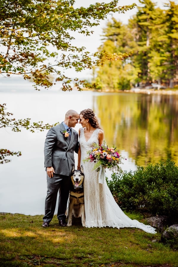 Bride and groom with husky dog in front of millinocket lake at big moose inn