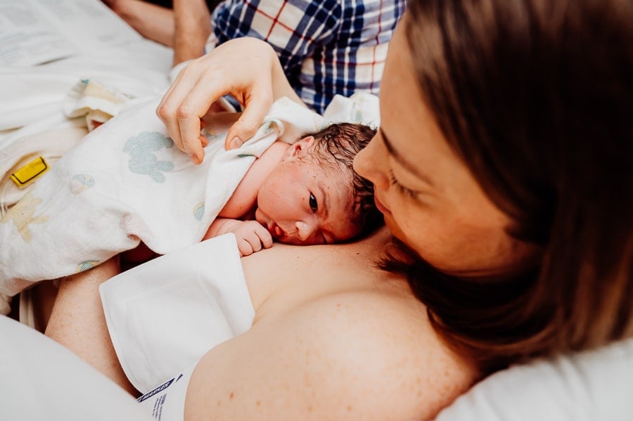 Mother with newborn baby laying on her chest in hospital bed