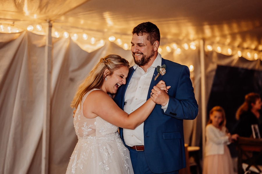Bride laughing while dancing with father at wedding