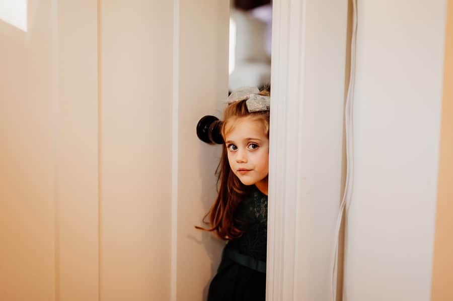 Flower girl peaking into room looking through door