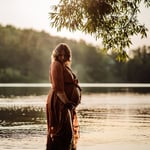 Woman wearing maternity gown in lake for photos
