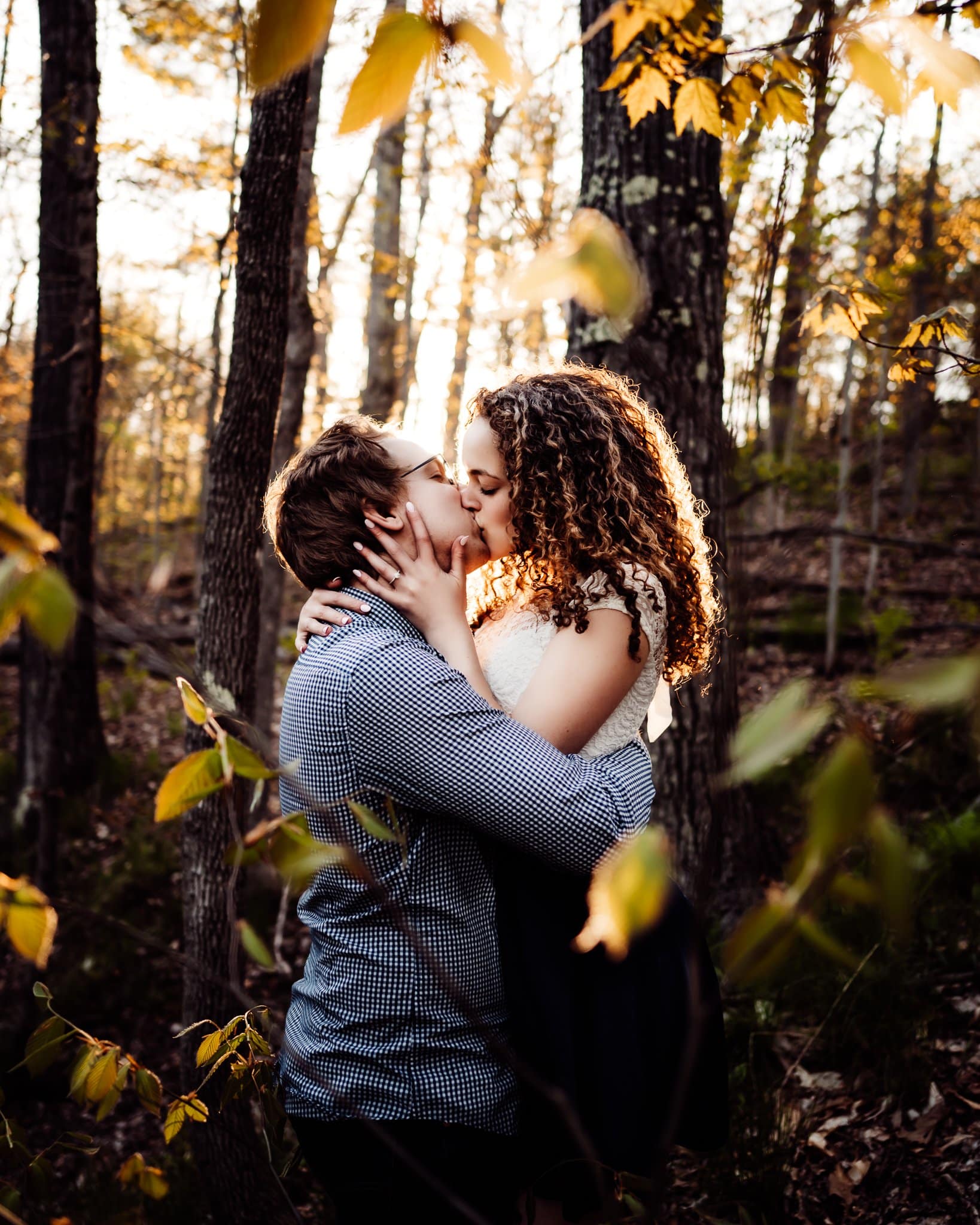 Engaged couple kissing in the woods