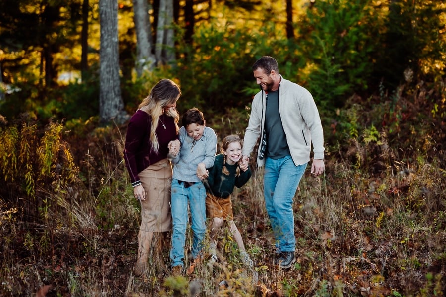 Family of four laughing and smiling together holding hands