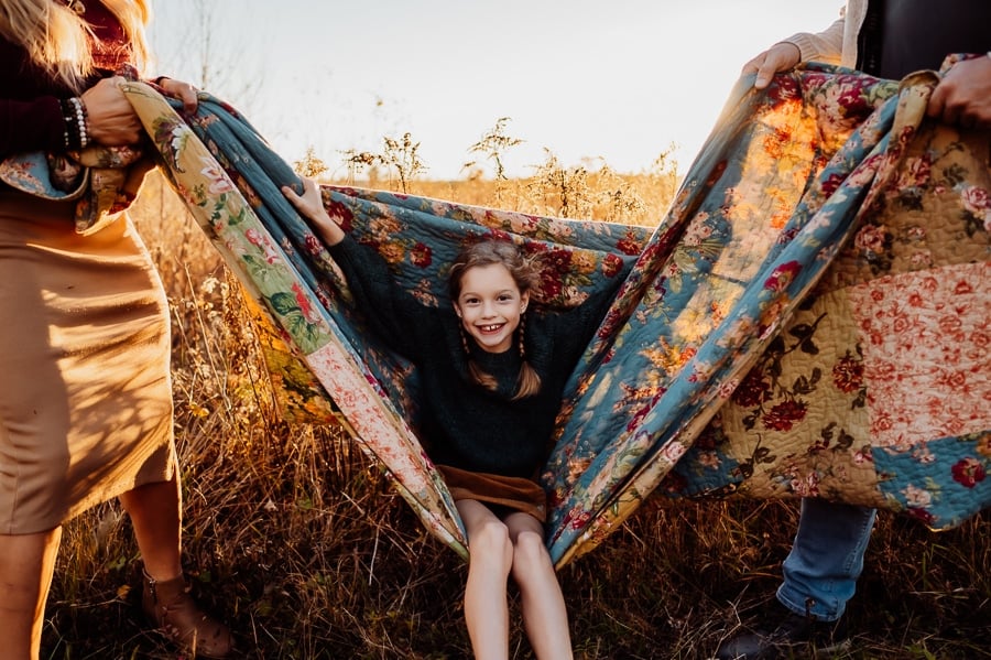 Little girl with blonde hair swinging on blanket