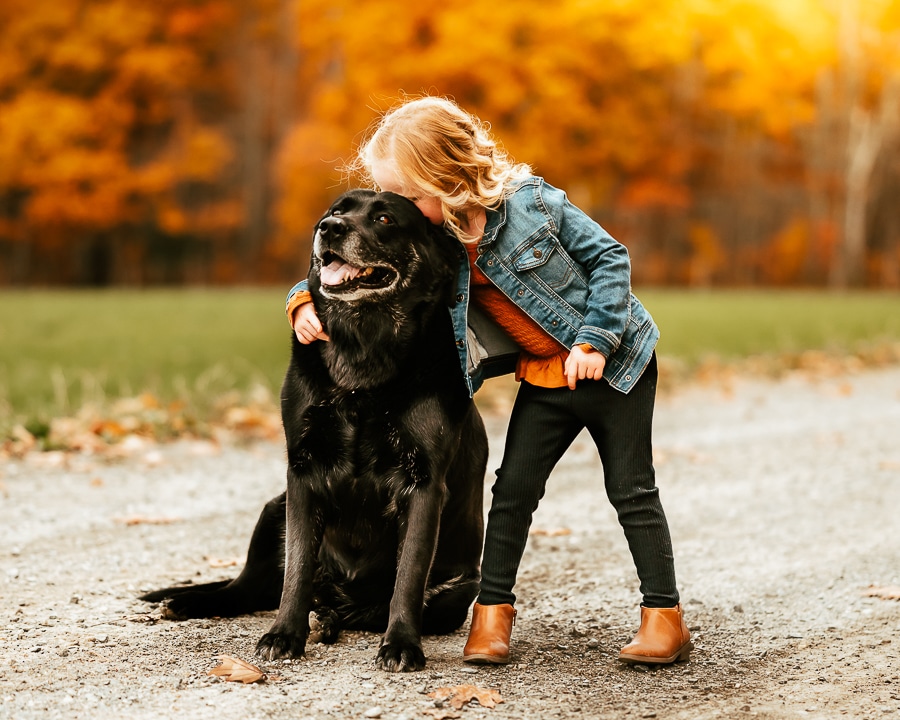 Little girl hugging black dog