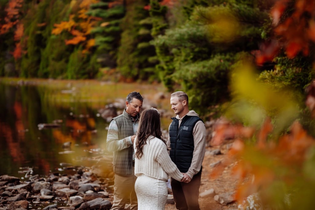 Intimate vow exchange framed by autumn leaves during Acadia fall elopement.