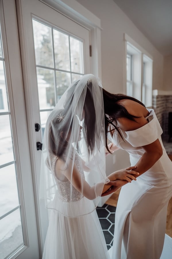 Bride standing with flower girl under veil