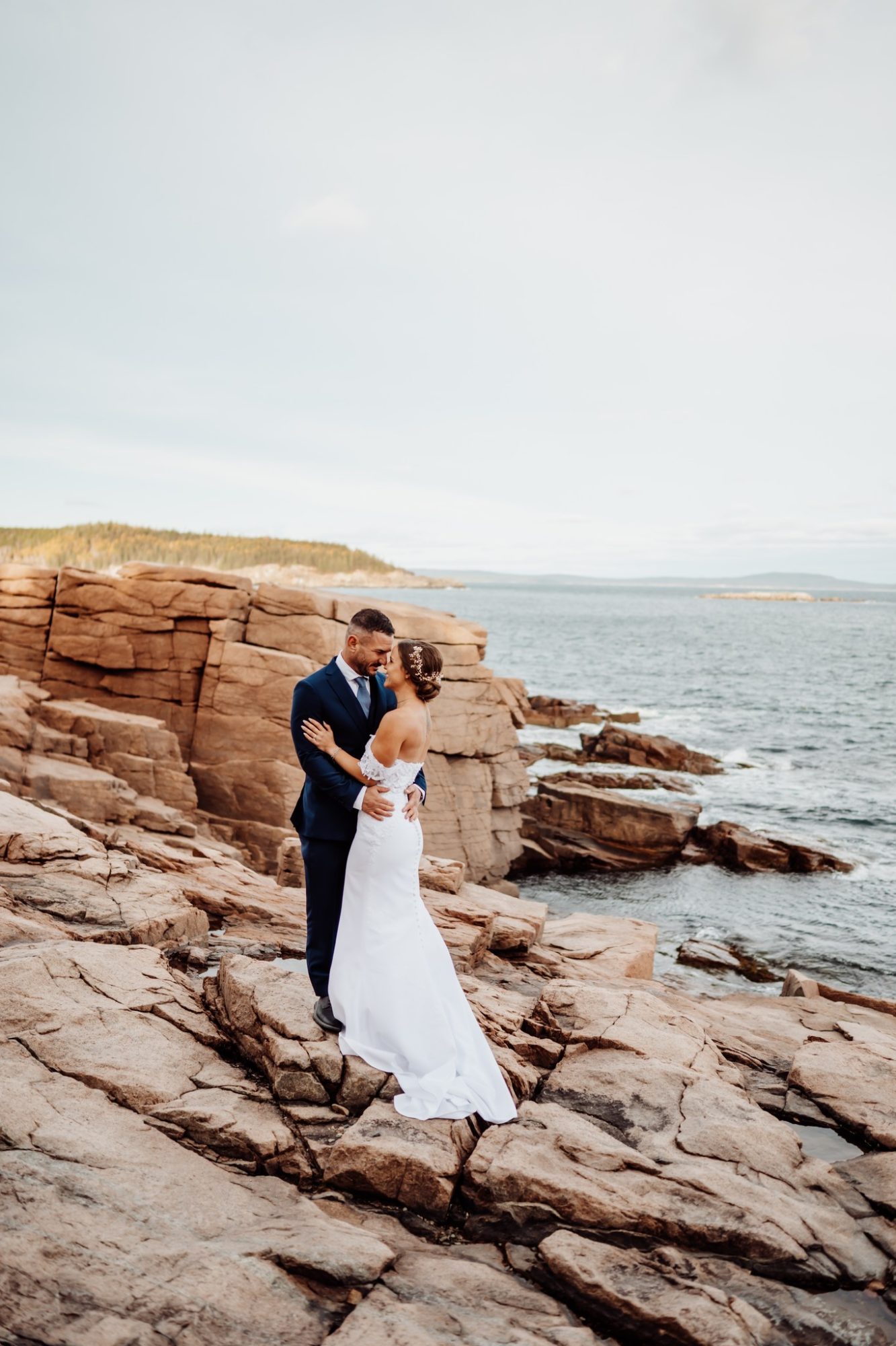 Intimate coastal portrait at Schooner Head Overlook in Acadia National Park with ocean and cliffs behind the couple.
