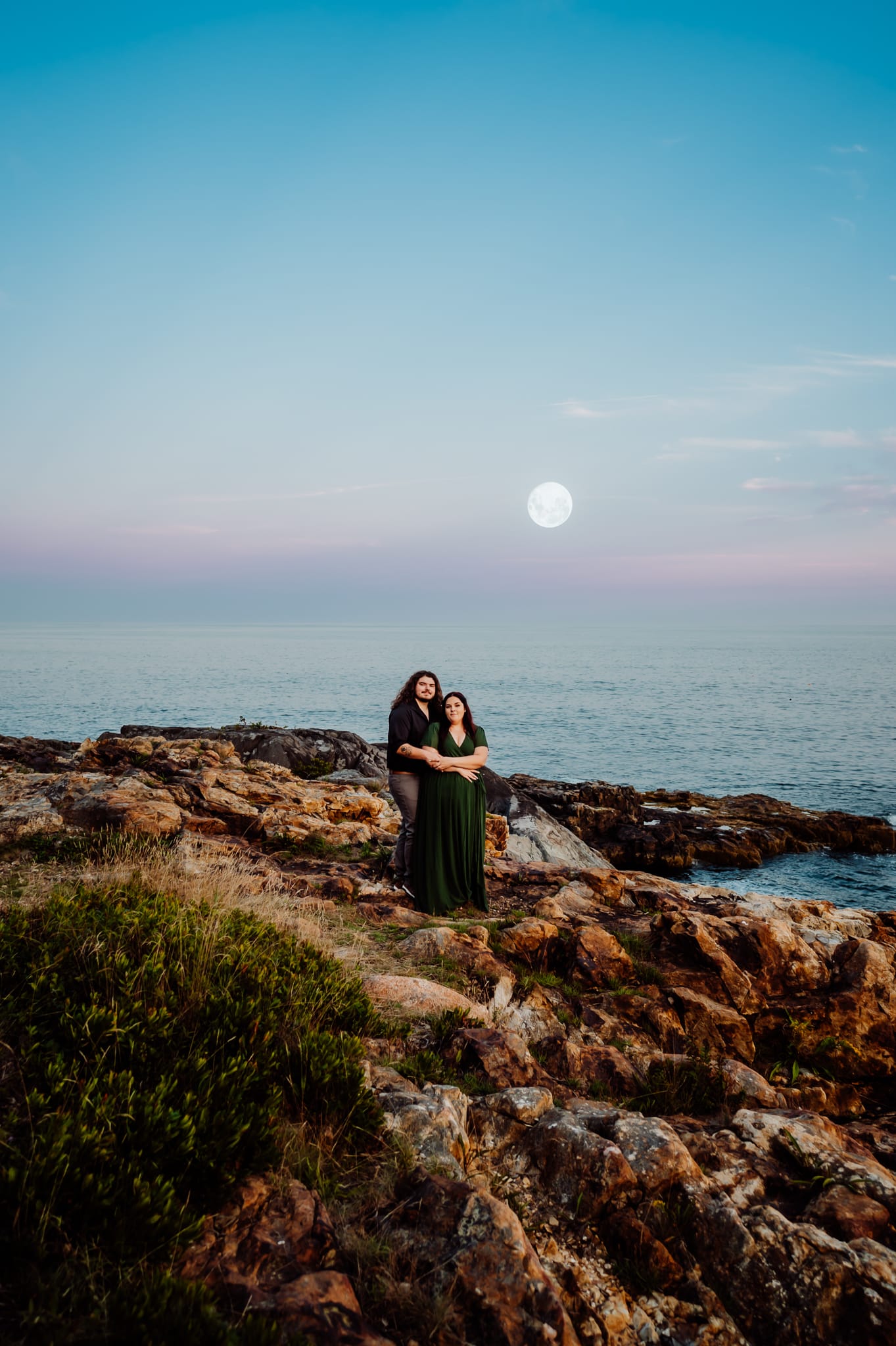 Engaged couple standing together on the rocky coast in Acadia national park