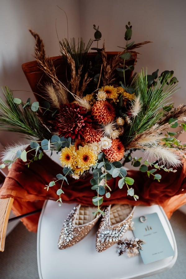 Wedding bouquet sitting on chair in corner with shoes below