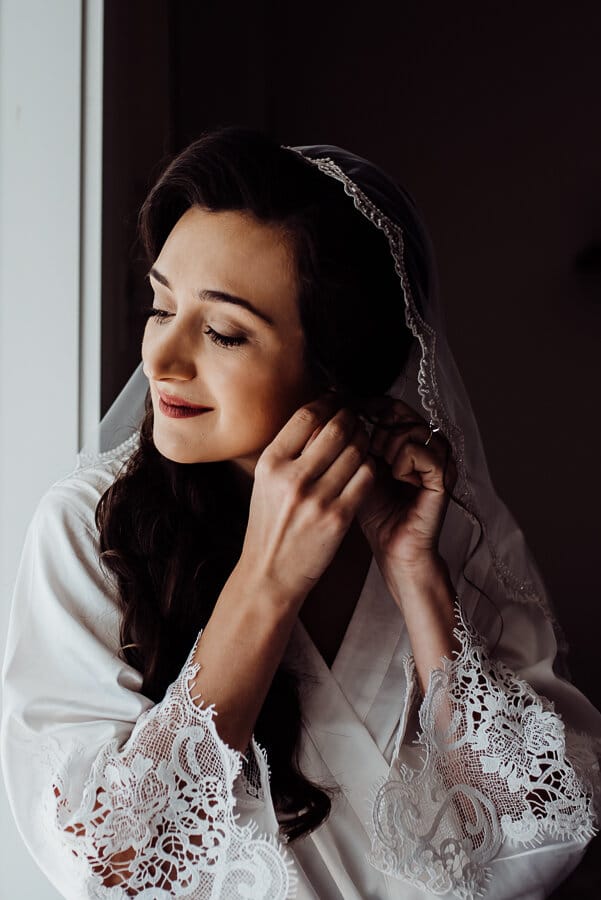 Bride putting on earring before maine wedding