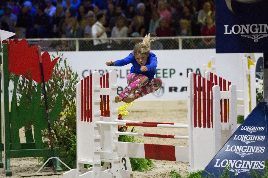 Girl jumping over horse jump