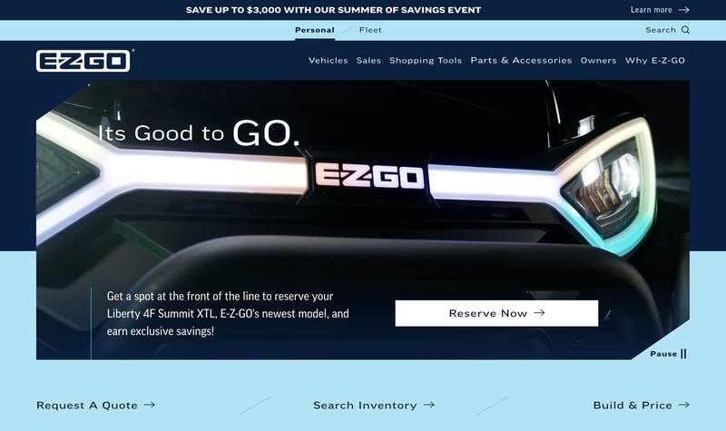E-Z-GO homepage hero featuring a close-up of a vehicle front end with illuminated headlights and a Reserve Now call to action
