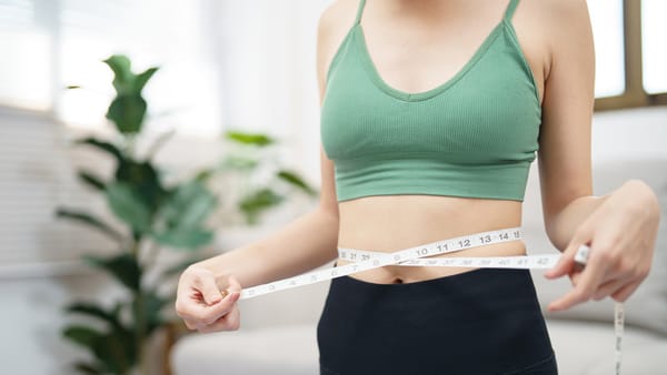 A woman holding a tape measure around her waist