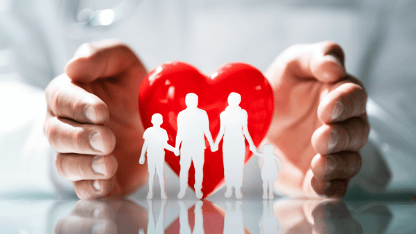 A person holding a red heart with a cutout of a family