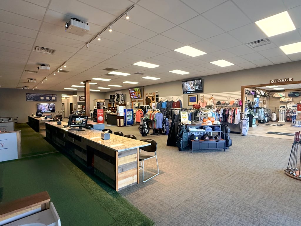 The shop floor with apparel racks beside the simulator bay counters