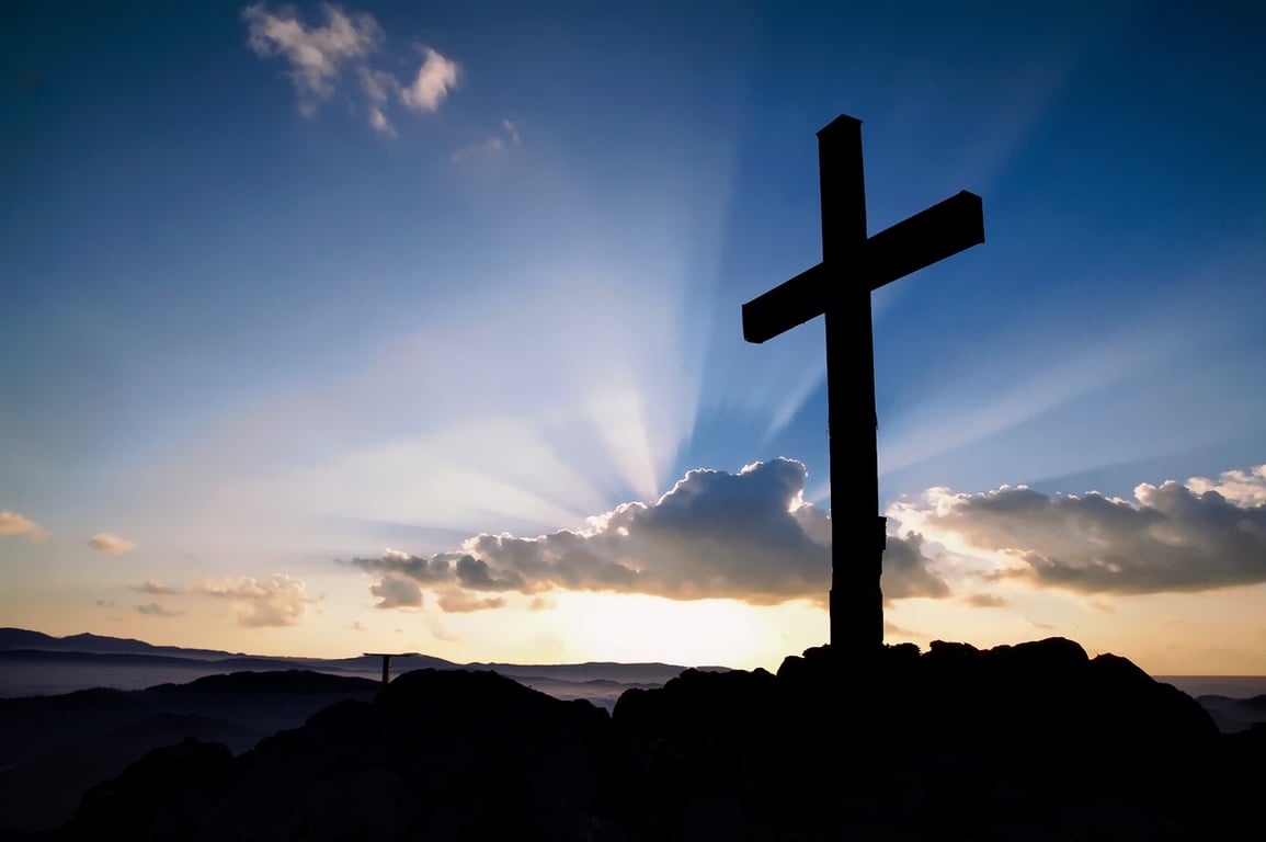 Christian Cross in the mountains, backlit by the sun