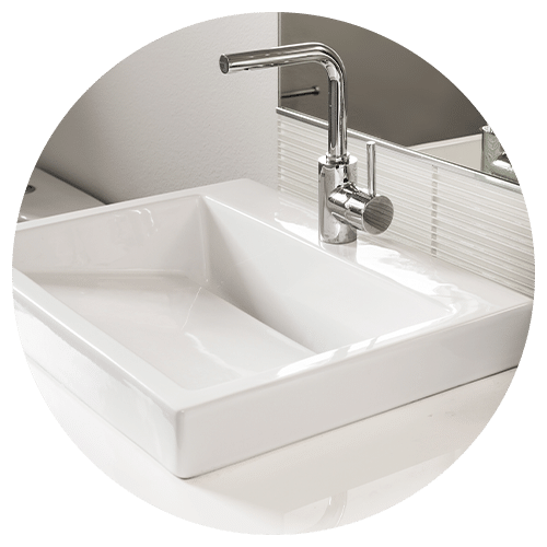 A modern white rectangular bathroom sink with a sleek chrome faucet, set on a glossy countertop in front of a striped glass backsplash and large mirror—perfect inspiration for your next kitchen remodel.