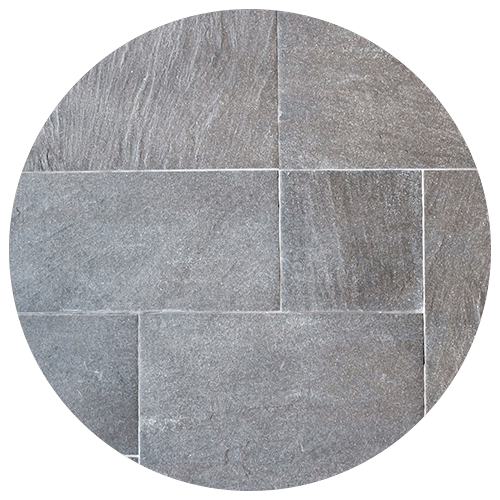 A circular image showing a pattern of rectangular gray stone tiles with visible texture and thin white grout lines between them—an elegant choice for any kitchen remodel.