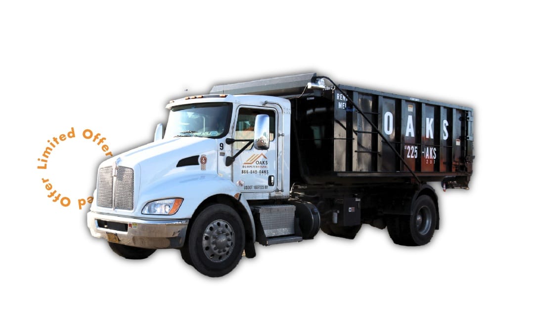 A white dump truck with a large black container on the back. The truck has a logo on the door that says Oaks Dispositions.
