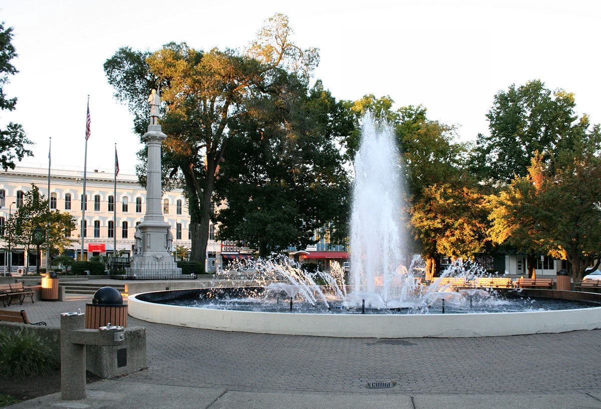 a fountain in a park, a building is visible in the background